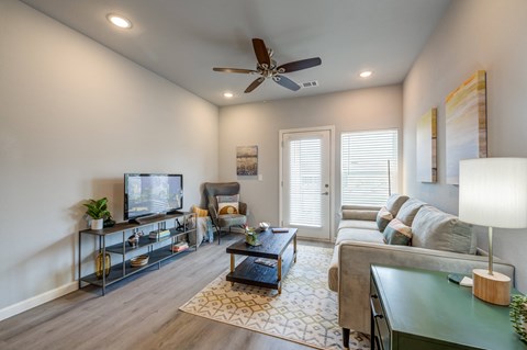 a living room with a ceiling fan and a tv